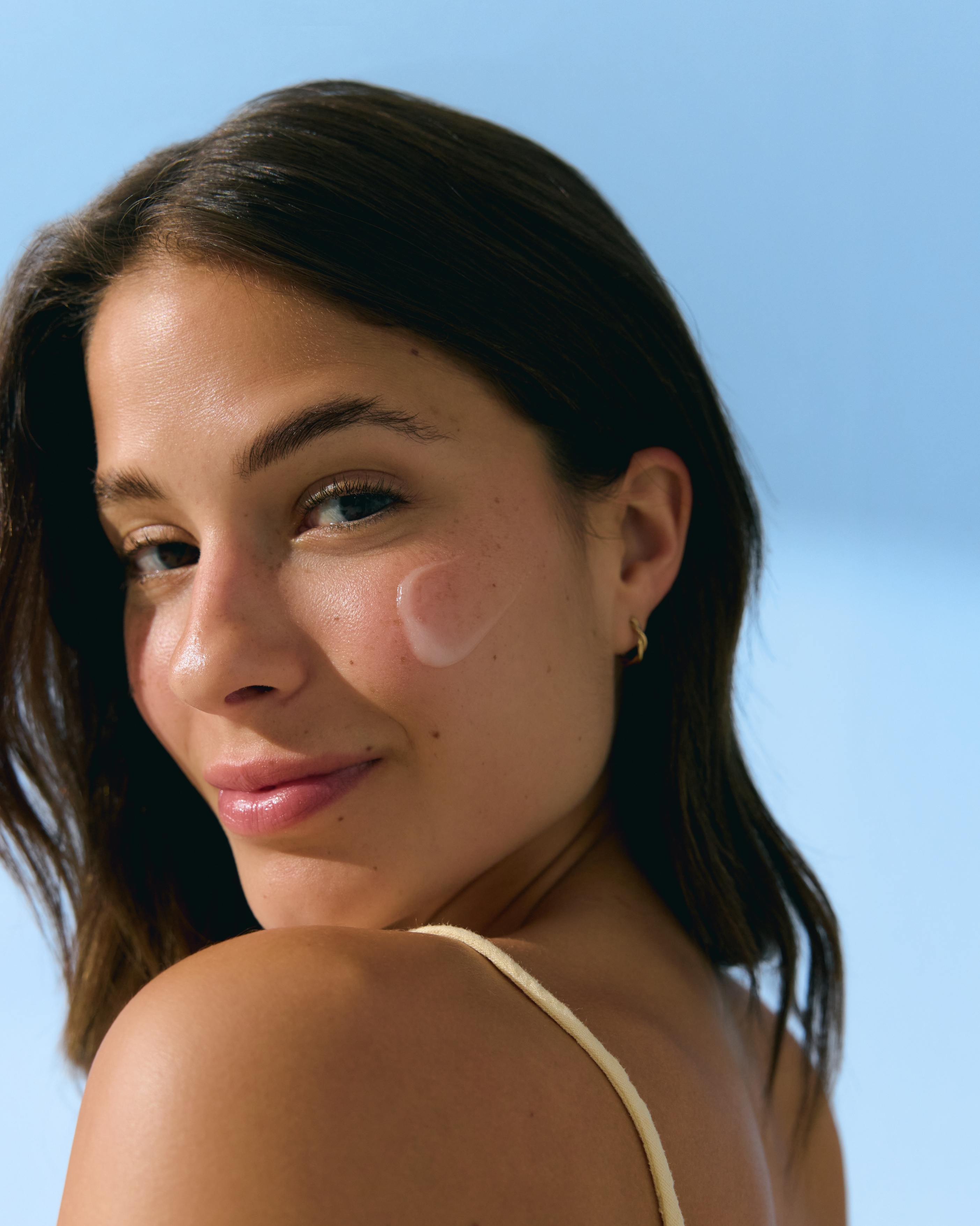 kvinna som tittar in i kameran och har kräm på kinden