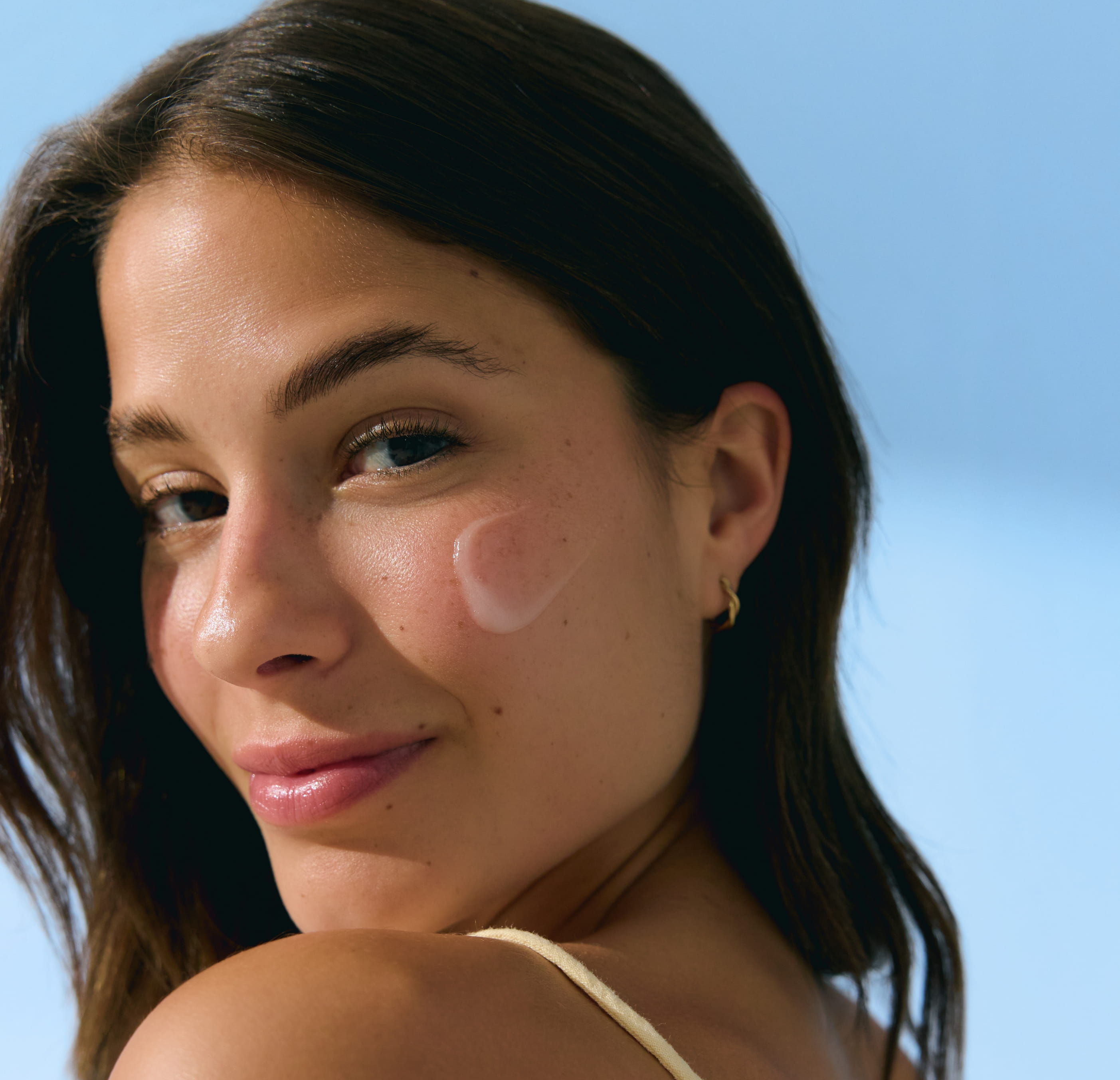 kvinna som tittar in i kameran och har kräm på kinden