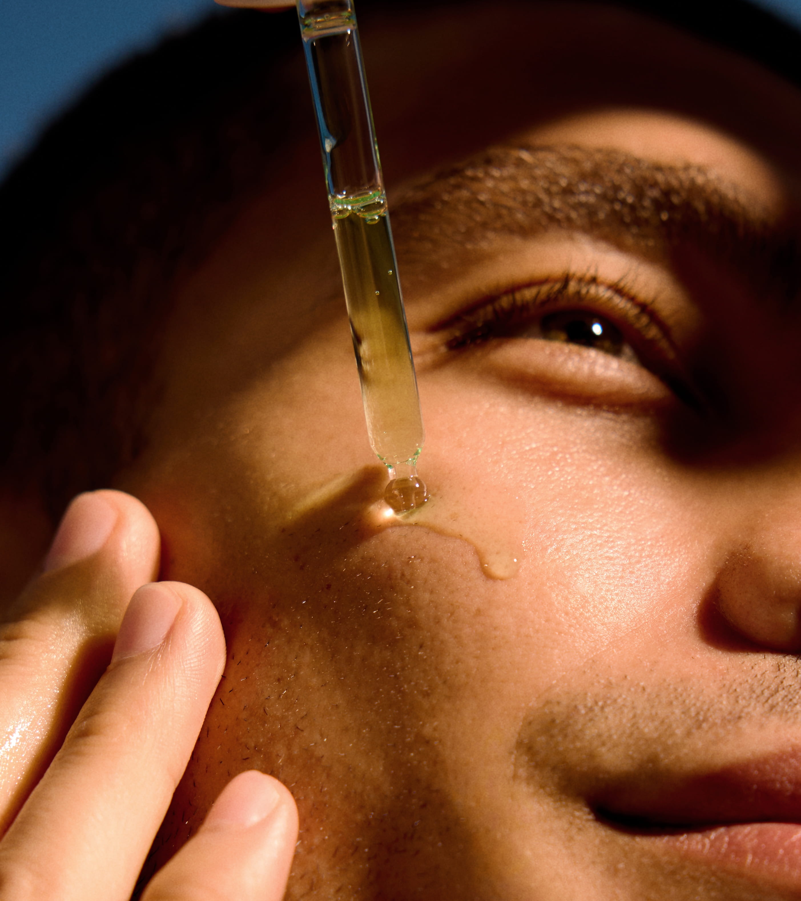 Inzoomad bild på mans ansikte som applicerar serum på kinden