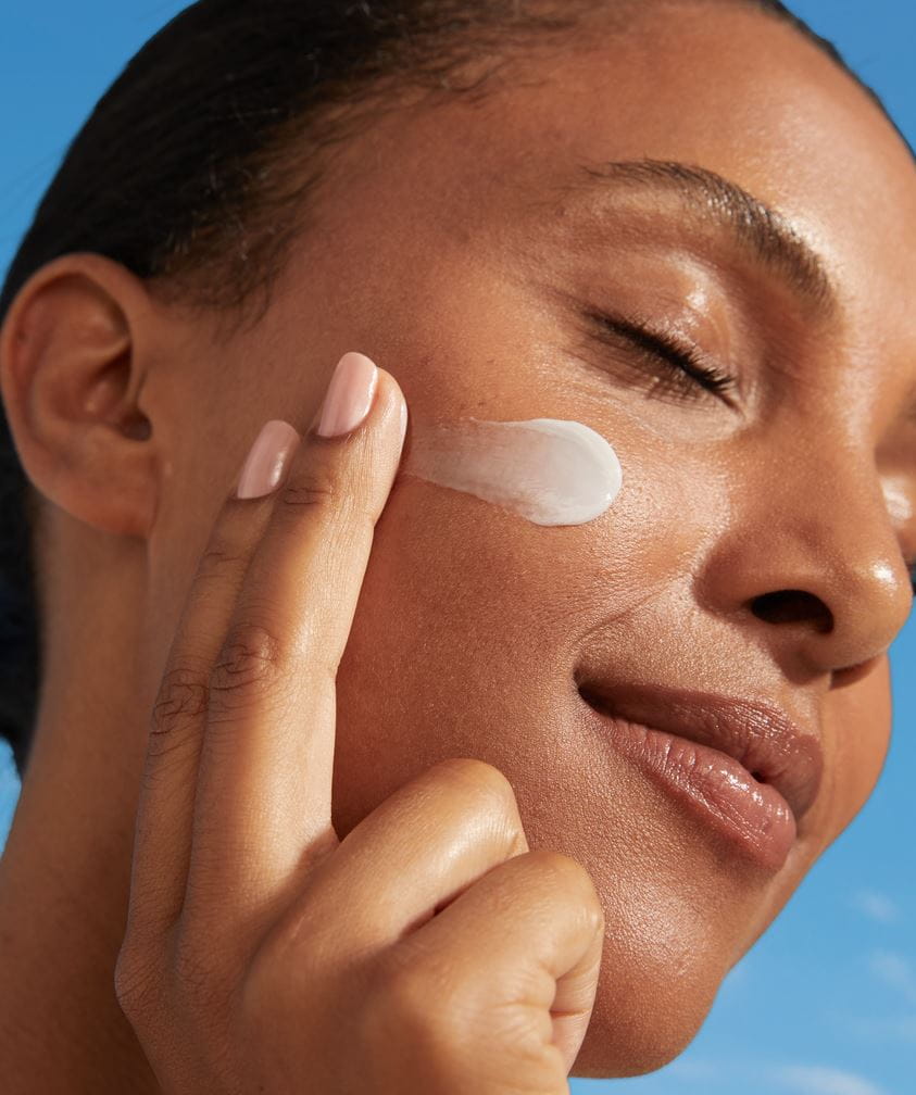 Mujer joven aplicando crema Nivea