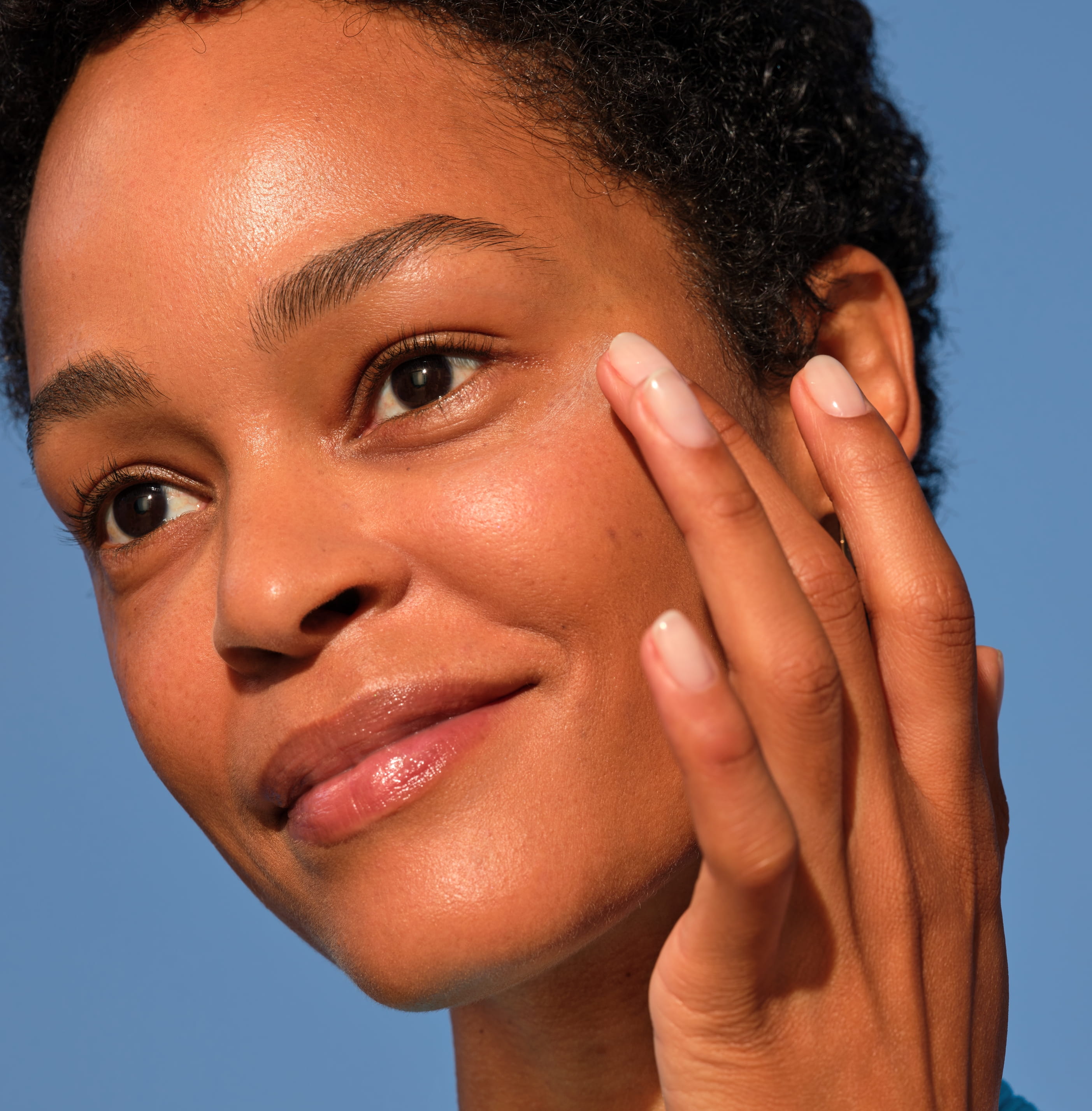 Person vidrör sin kind med ena handen och tiltar huvudet och ler