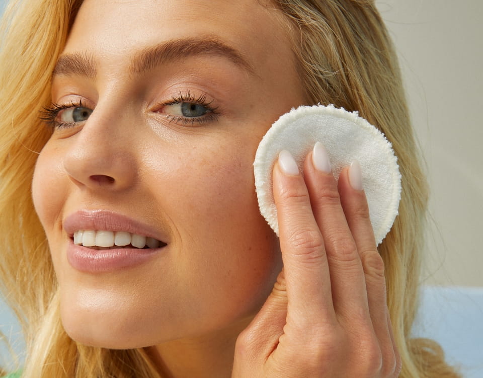 Jonge vrouw die haar gezicht reinigt