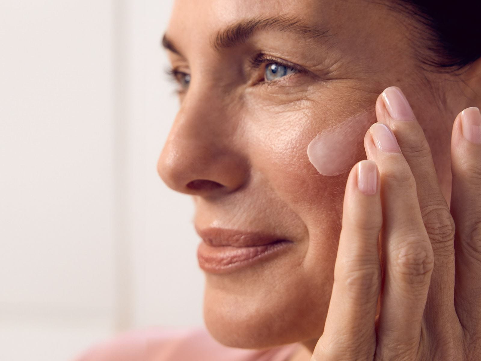 Une personne regardant au loin avec un produit NIVEA étalé sur le côté gauche de son visage.