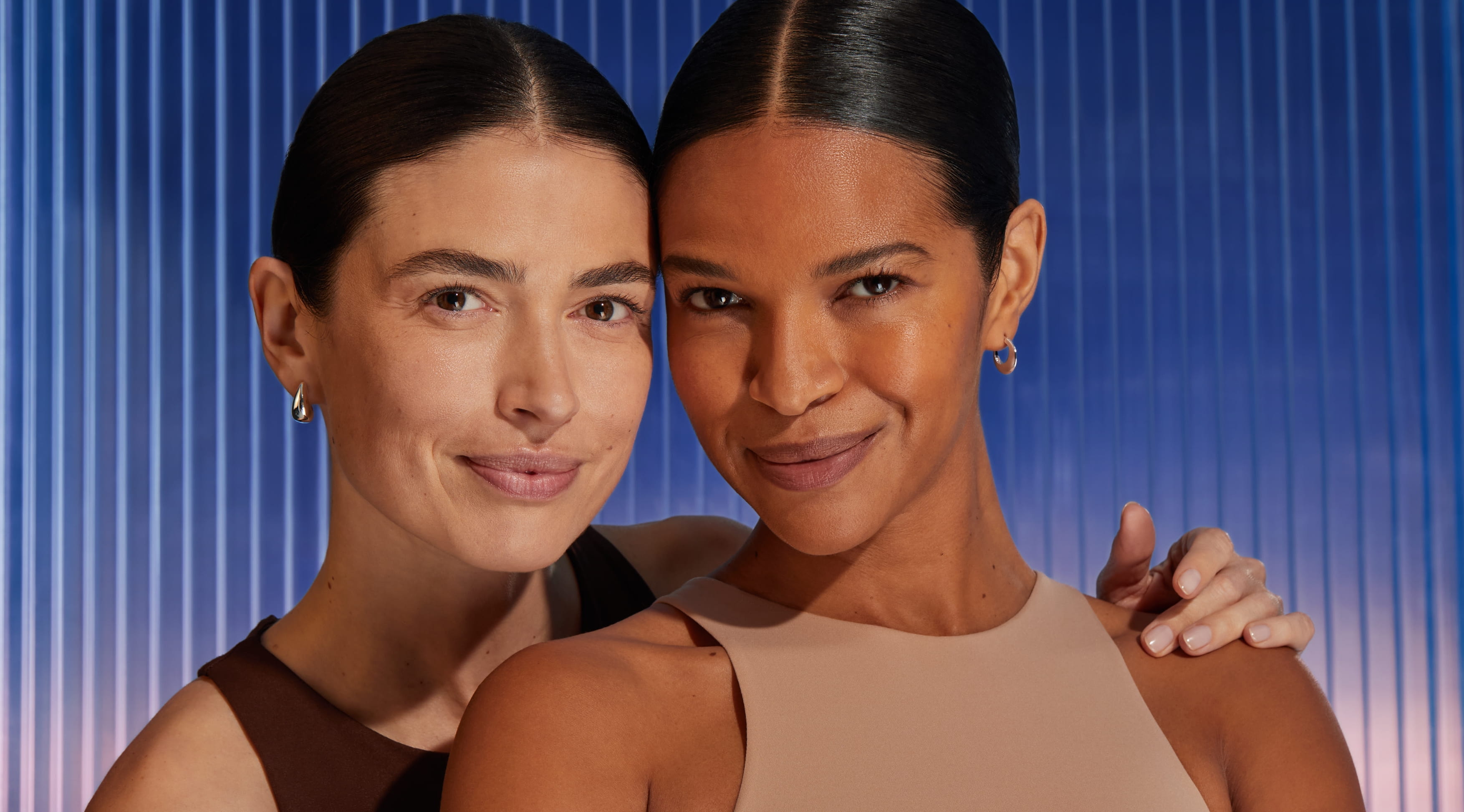 Två kvinnor ler in i kameran