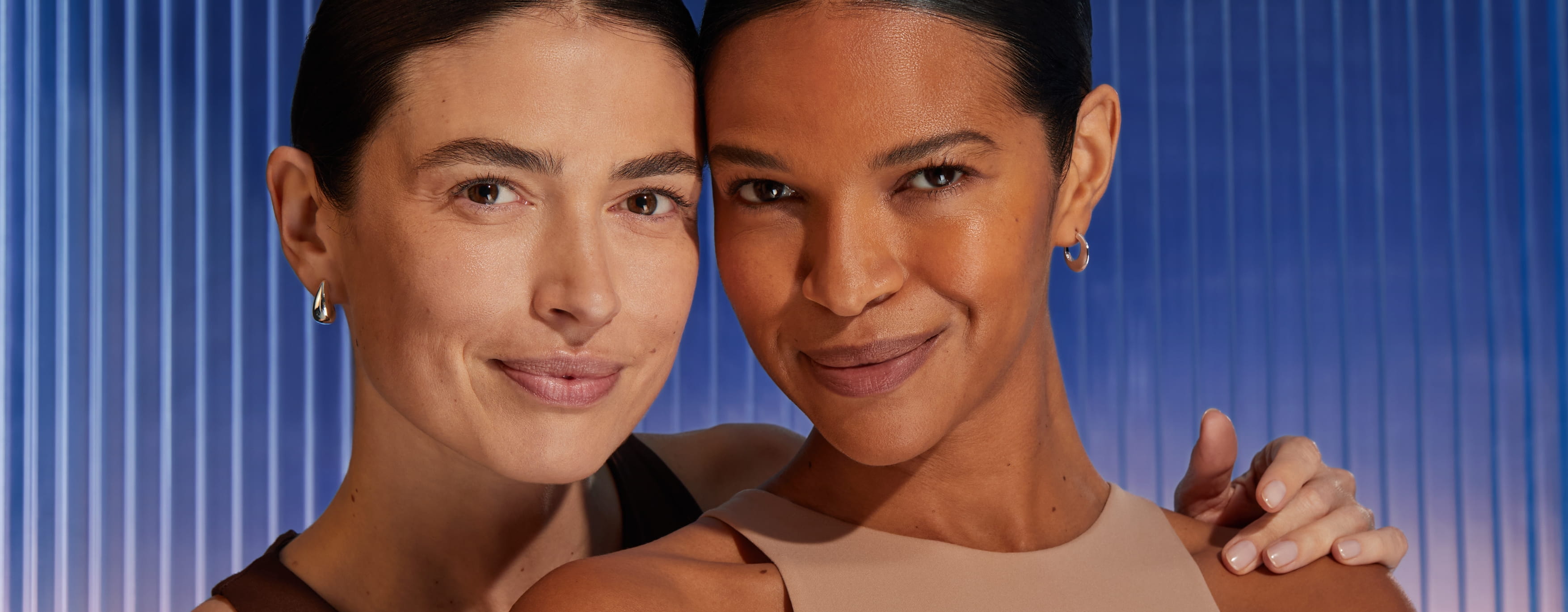 Två kvinnor ler in i kameran