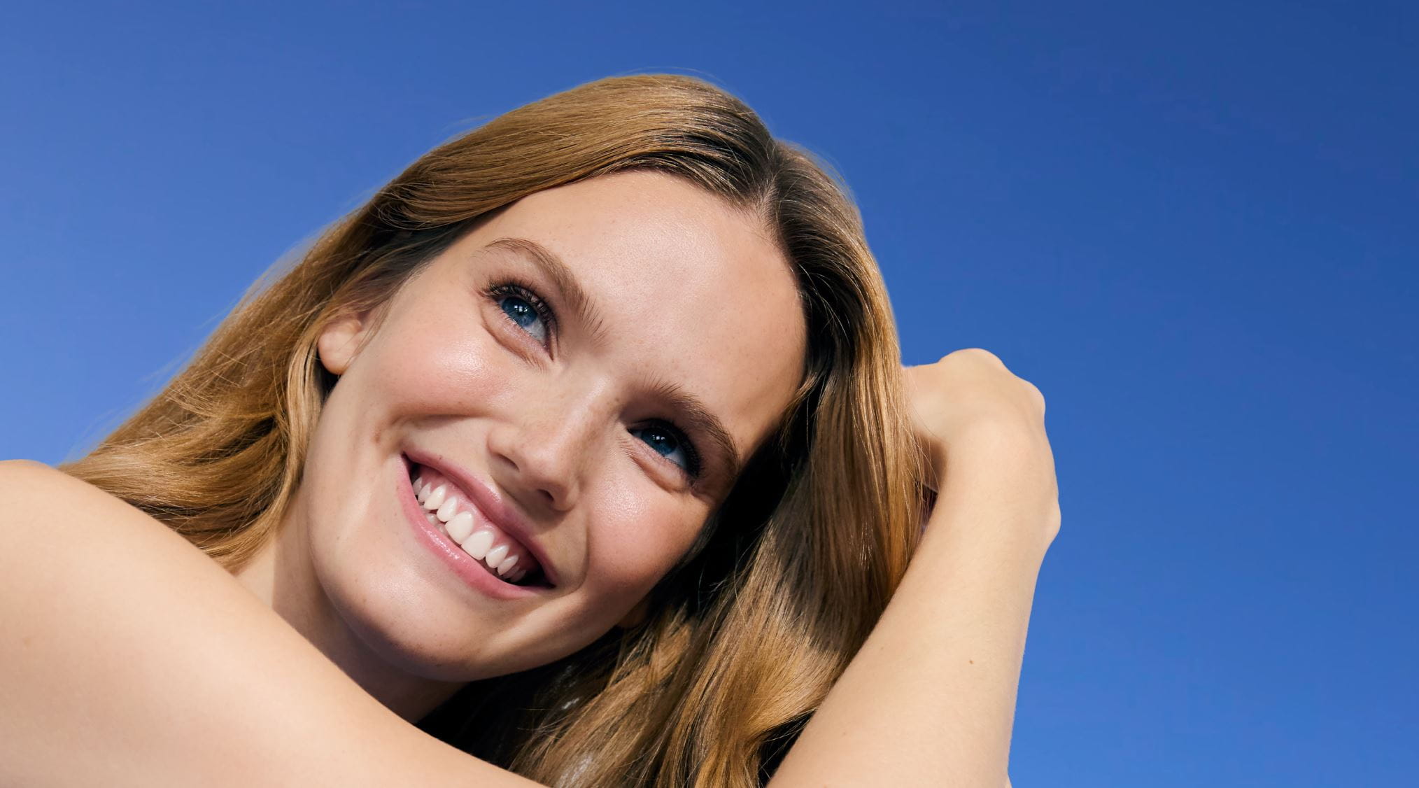 Mulher com a mão no cabelo e sorrindo