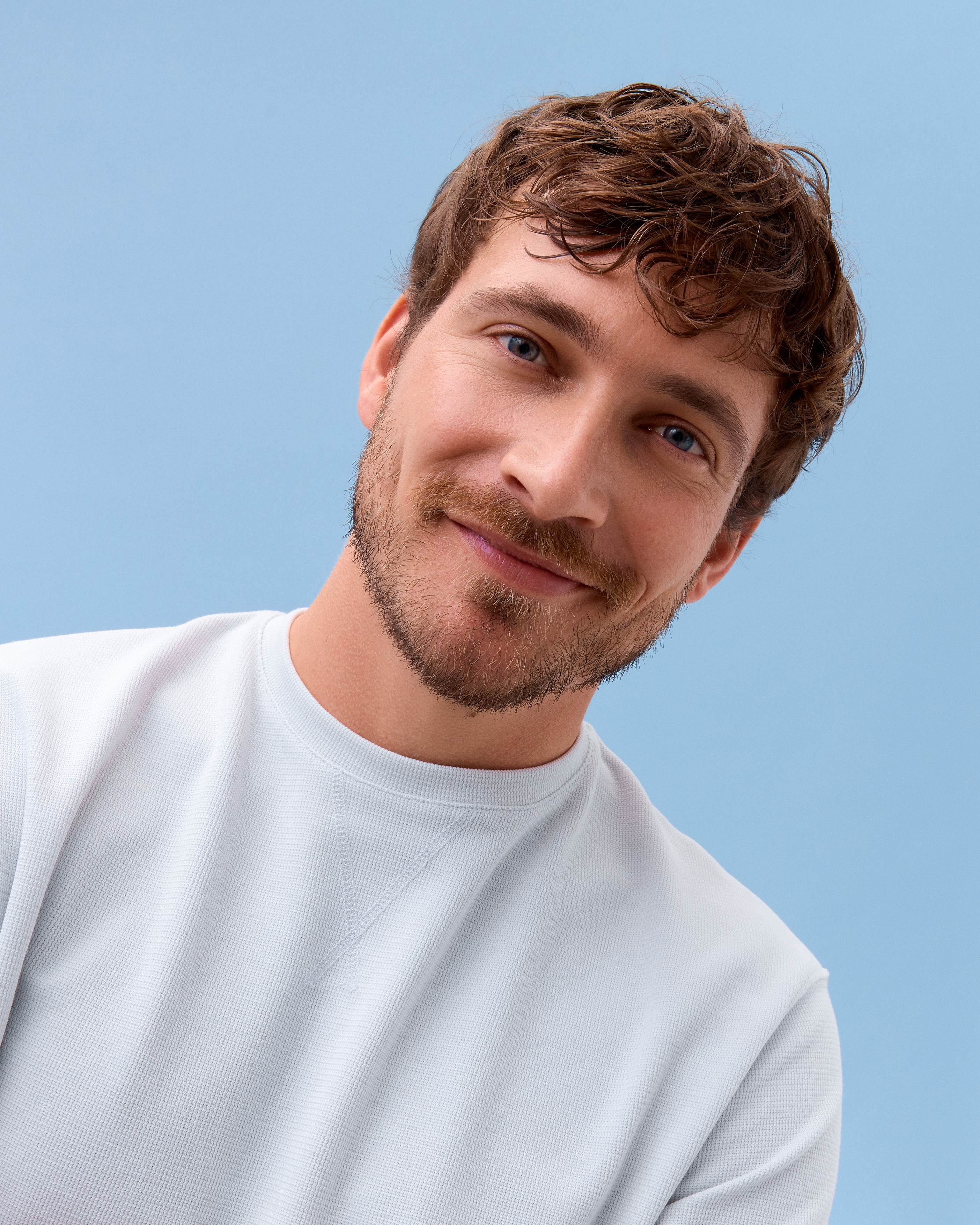 En person som tittar in i kameran och har en vit t-shirt på sig
