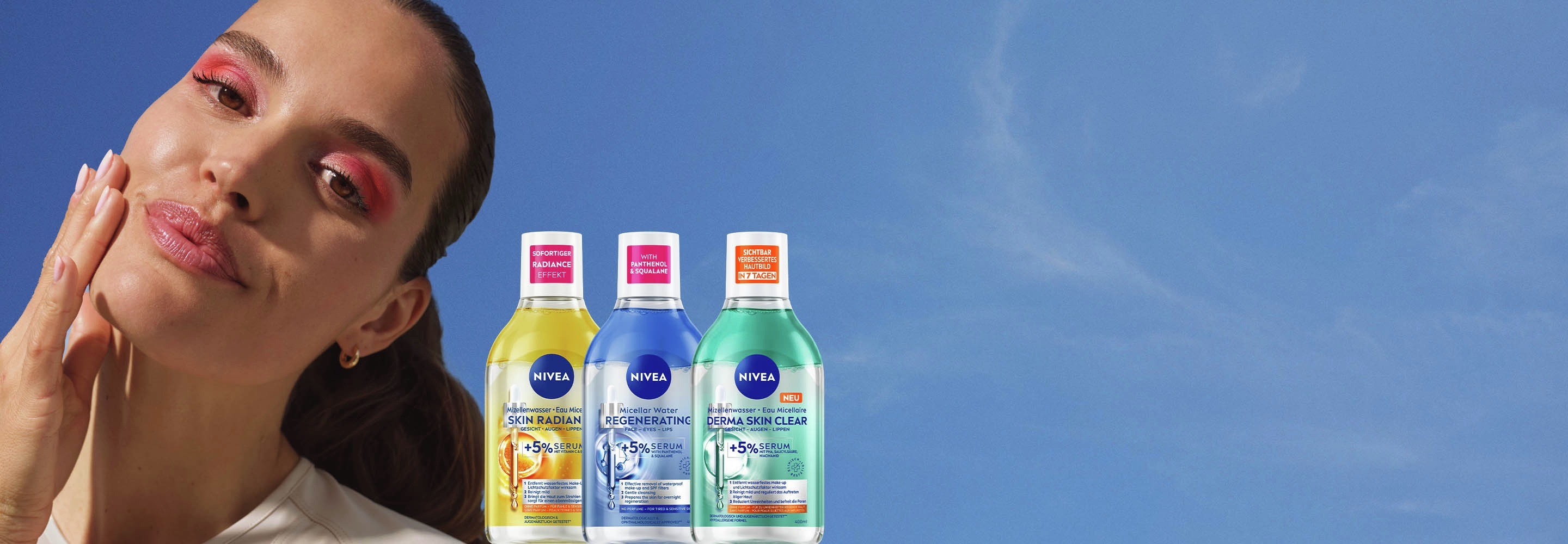 Lächelnde Frau mit pinkem Lidschatten, berührt ihr Gesicht, neben dem NIVEA Serum-infused Mizellenwasser