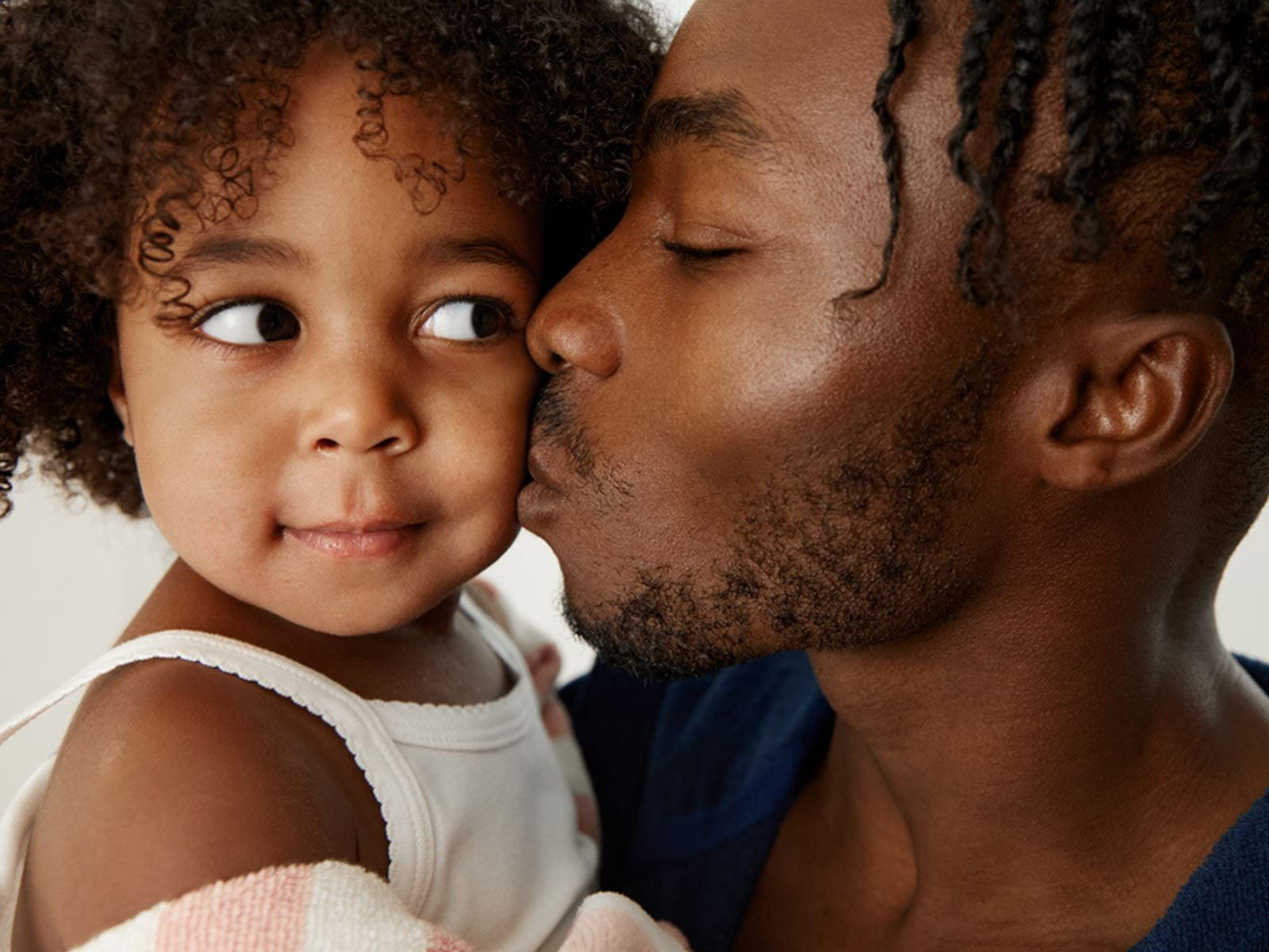 View of an adult kissing the cheek of a toddler.