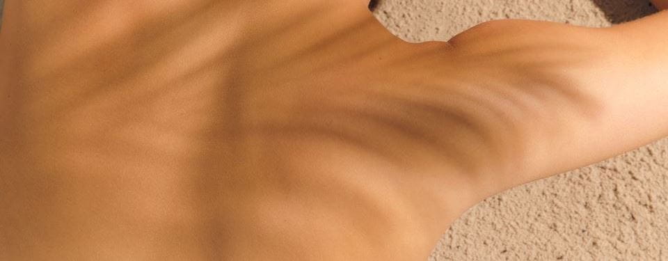 Vrouw smeert zonnecrème op schouder