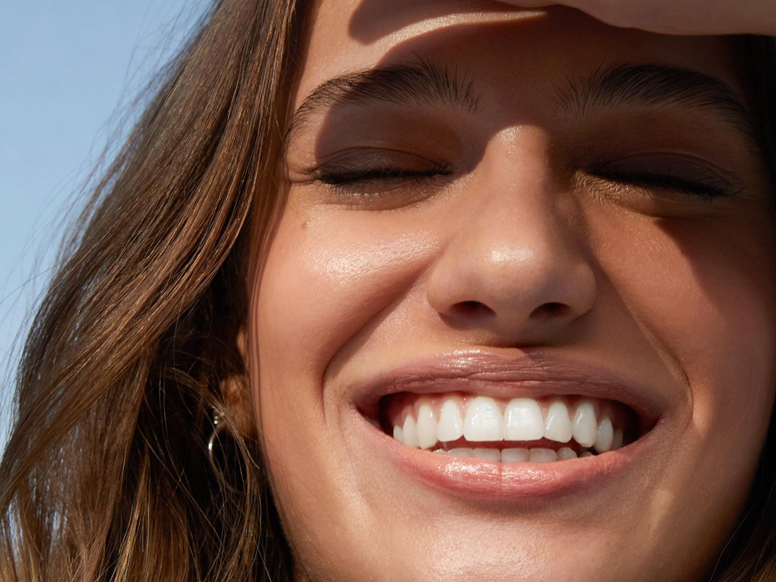 View of a person with their eyes closed smiling wide.