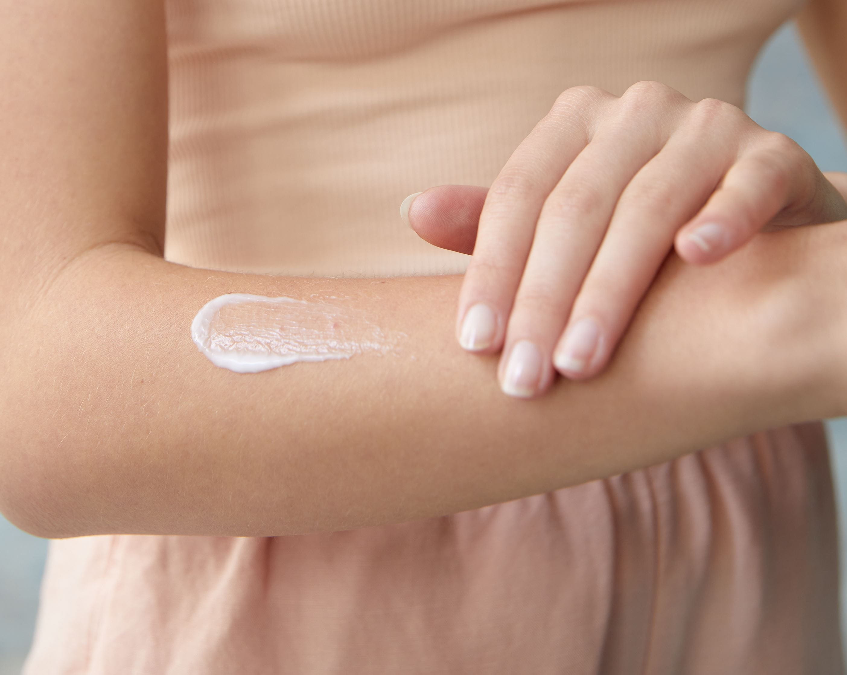 femme mettant de la lotion corporelle sur son bras