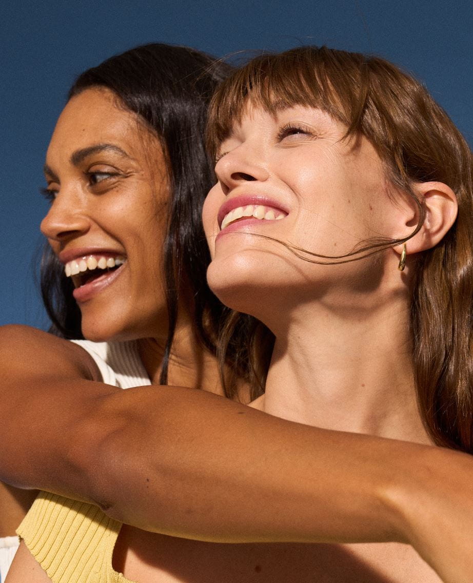 Två kvinnor som håller om varandra och ler