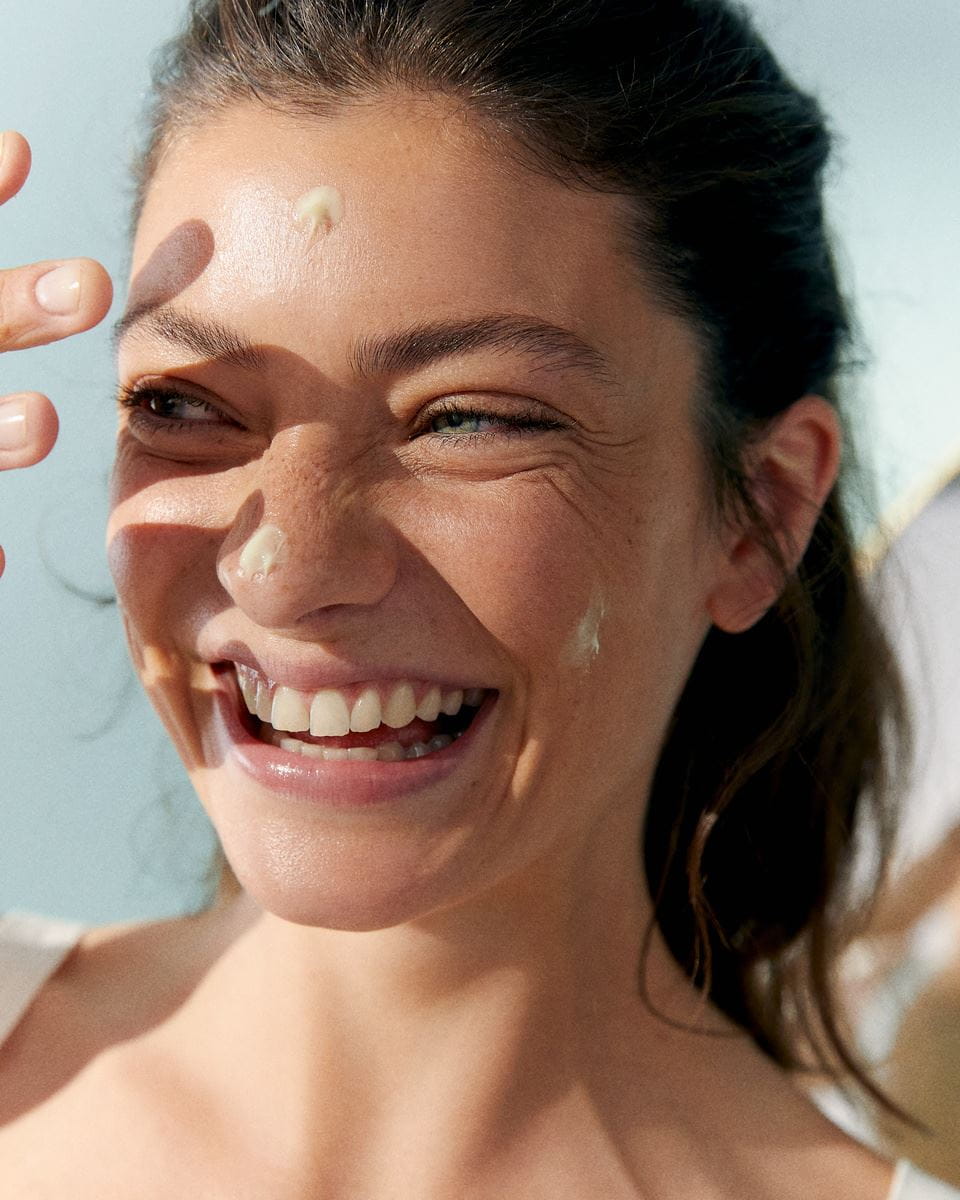 woman smiling, holding a Nivea serum