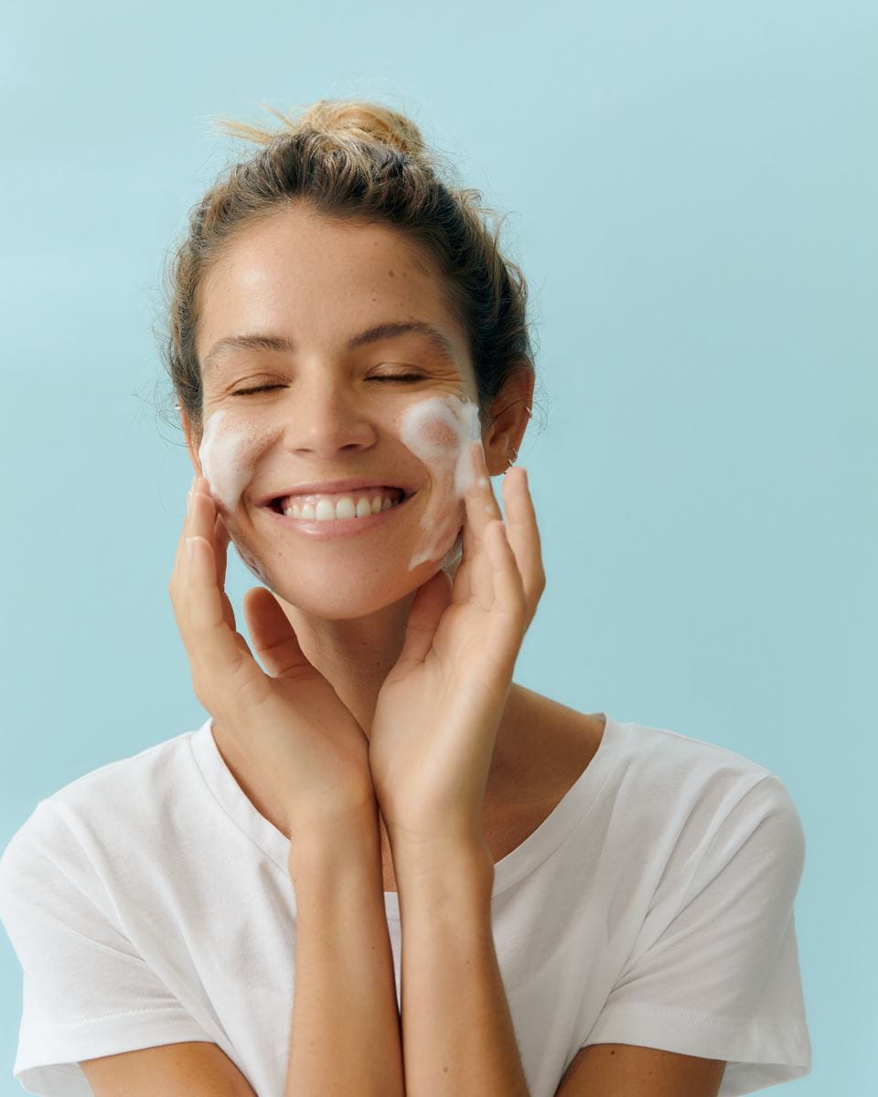 woman washing her face with vegan skincare product