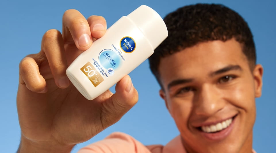 Młody mężczyzna używający Nivea Sun Invisible Fluid 50+
