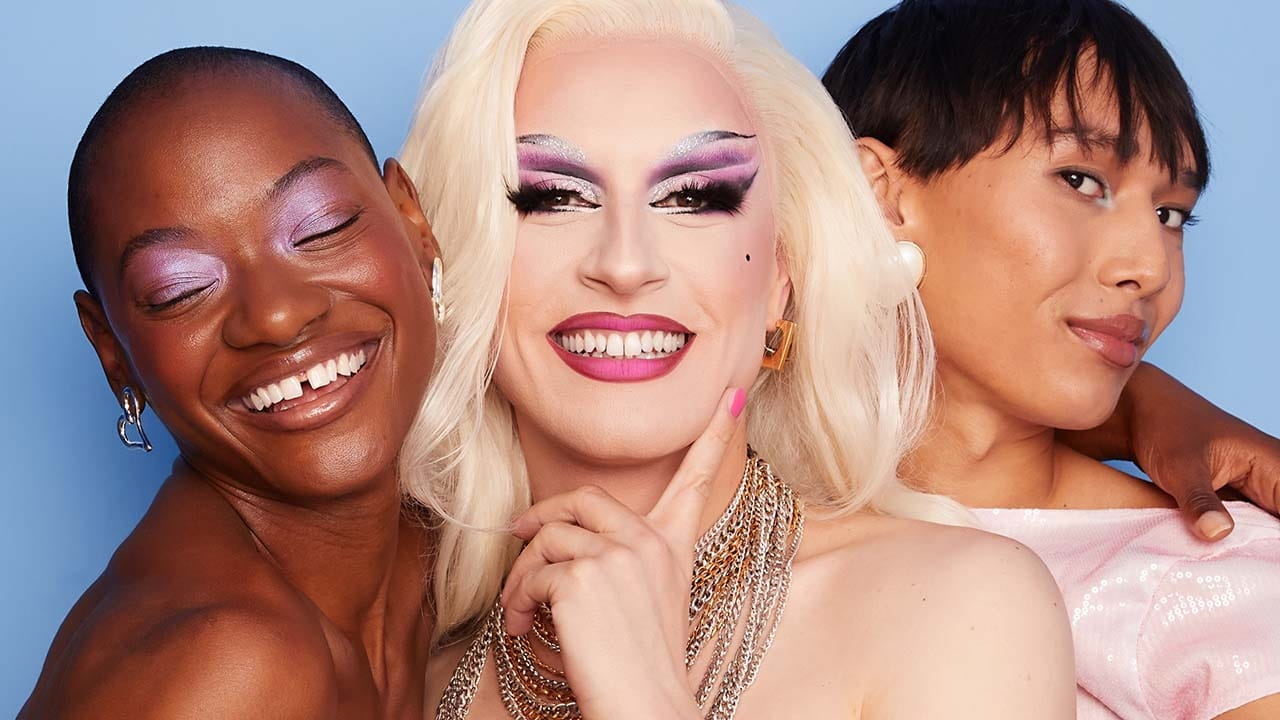 Three people seen smiling and laughing together while embracing.