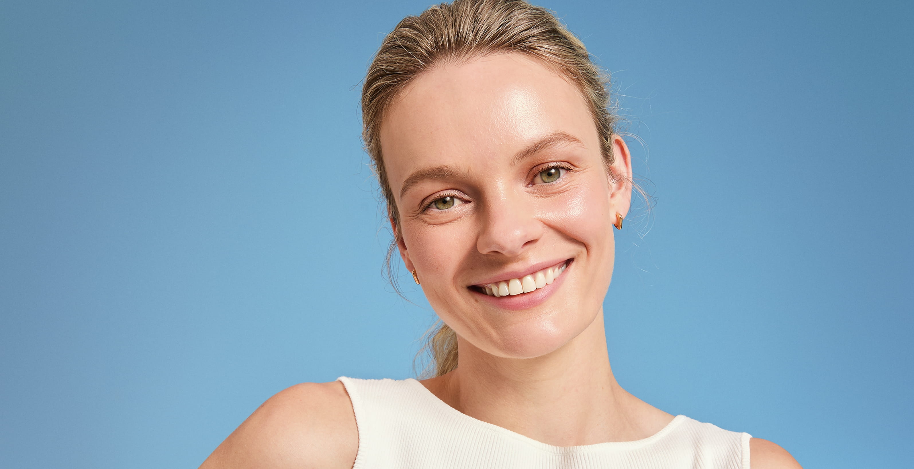 En person som tittar in i kameran och ler med blå bakgrund