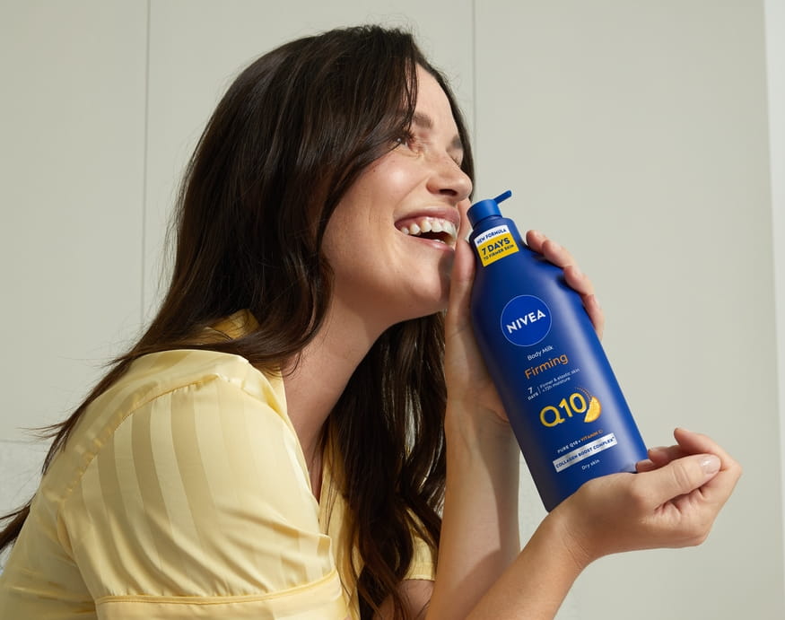 Jonge vrouw die Nivea Q10 Body Lotion gebruikt