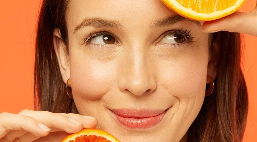 mulher segurando duas laranjas cortadas ao meio