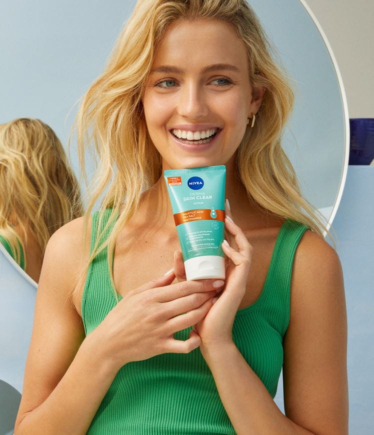 Mujer joven usando Nivea Derma Skin Clear Scrub