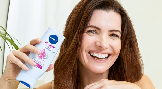 Junge Frau mit dunklem Haar, die Diamond Gloss Brillant Spülung verwendet