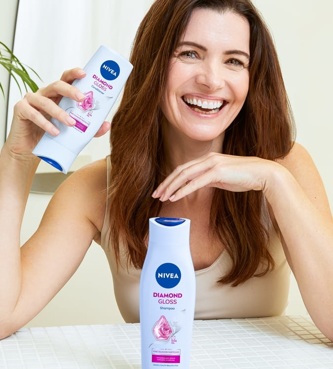 Junge Frau mit dunklem Haar, die Diamond Gloss Brillant Spülung verwendet