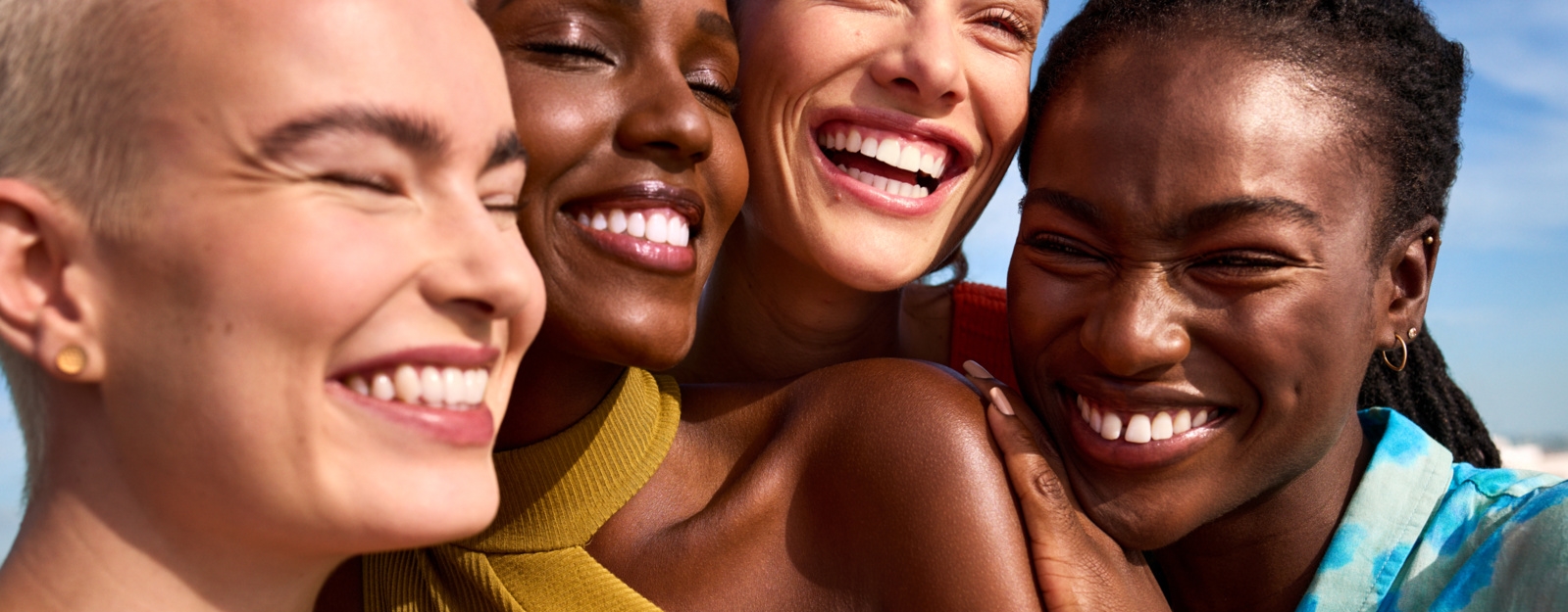 Cuatro personas posando y sonriendo con su piel radiante