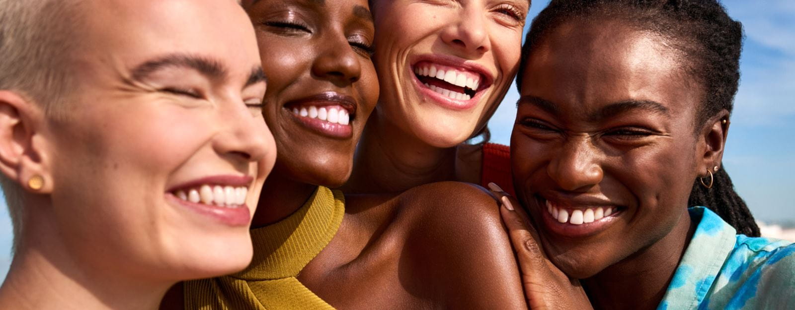 Cuatro personas posando y sonriendo con su piel radiante