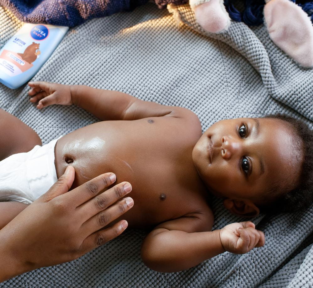 Eine Mutter trägt Babyöl auf die Haut ihres Babys auf