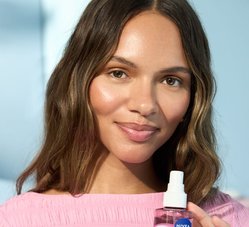 Jonge vrouw die Nivea Rose Care Hydrating Face Mist gebruikt
