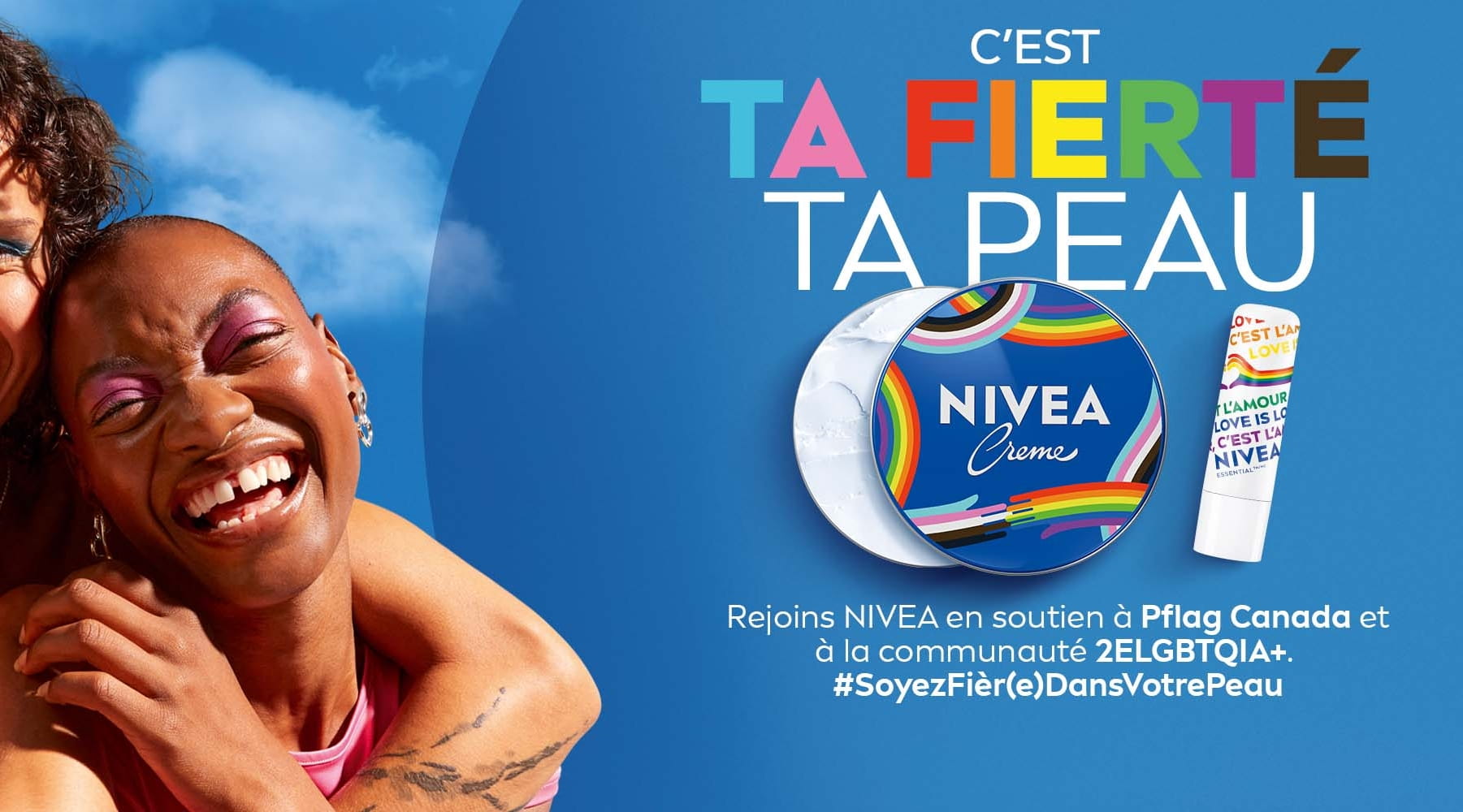 Deux personnes souriantes s'entrelaçent sur fond de ciel bleu, avec Pot NIVEA CREME Fierté série limitée et baume à lèvres NIVEA Essential Fierté série limitée, pour promouvoir la campagne « Soyez fièr(e) dans votre peau » en soutien à la communauté 2SLGBTQIA+.