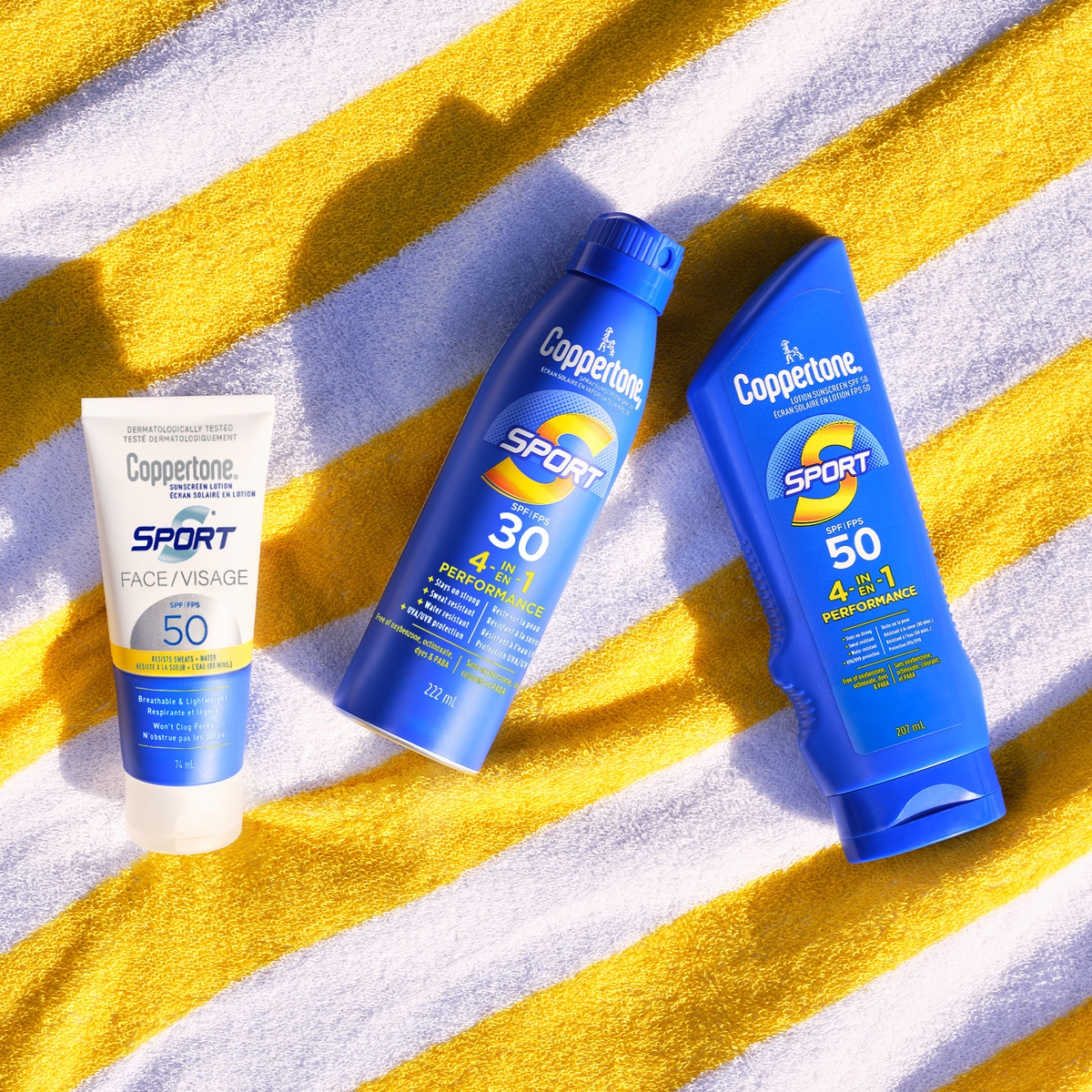 Three Coppertone Sport sunscreen products on a yellow striped beach towel