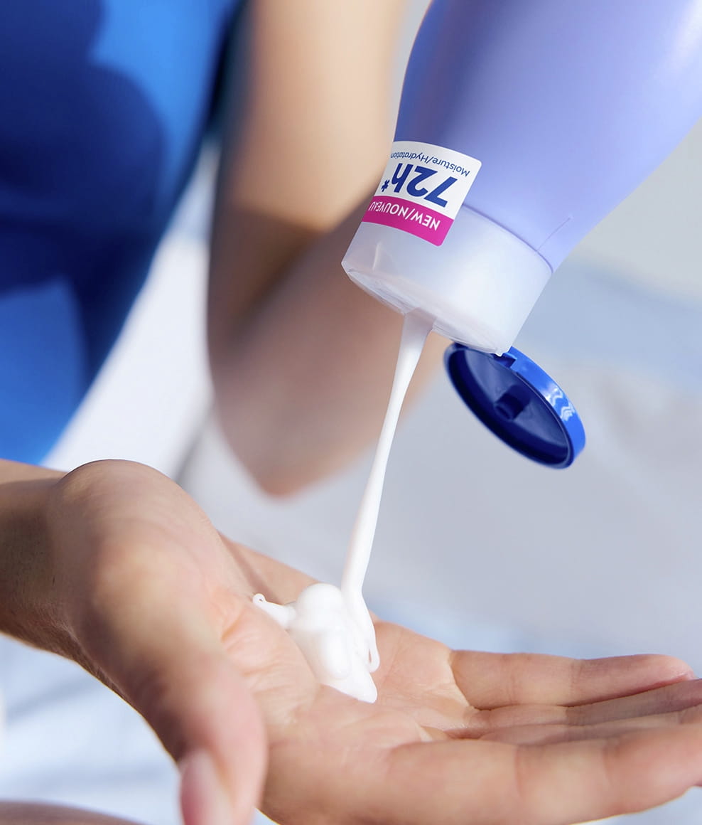 A close-up of creamy NIVEA Smooth Body Lotion being squeezed from the bottle into a person's cupped hand.