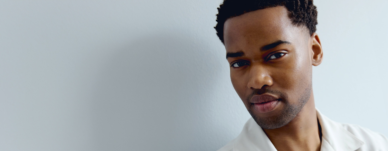 View of a person peering into the camera, against a grey background.