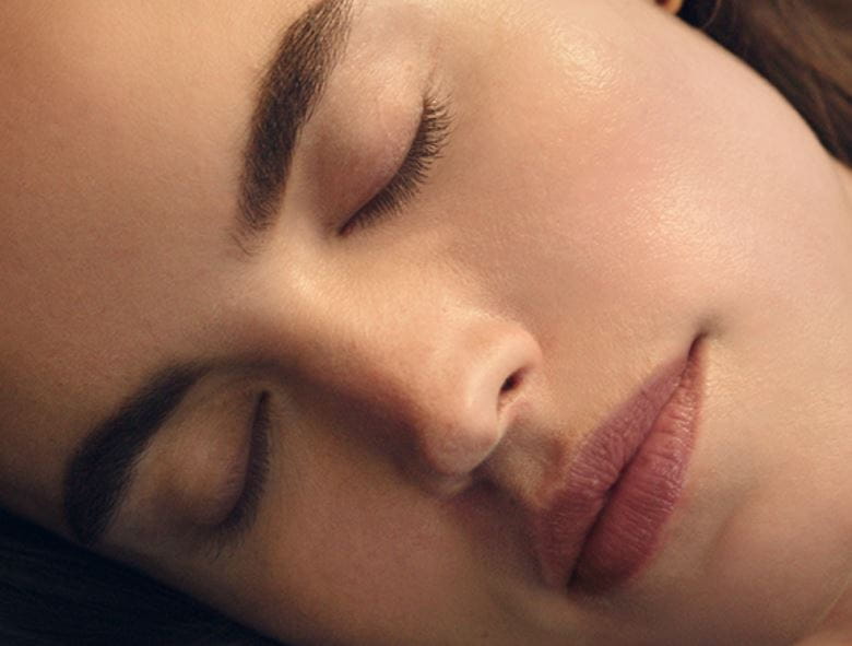 Woman with clear and healthy skin sleeping deeply in bed