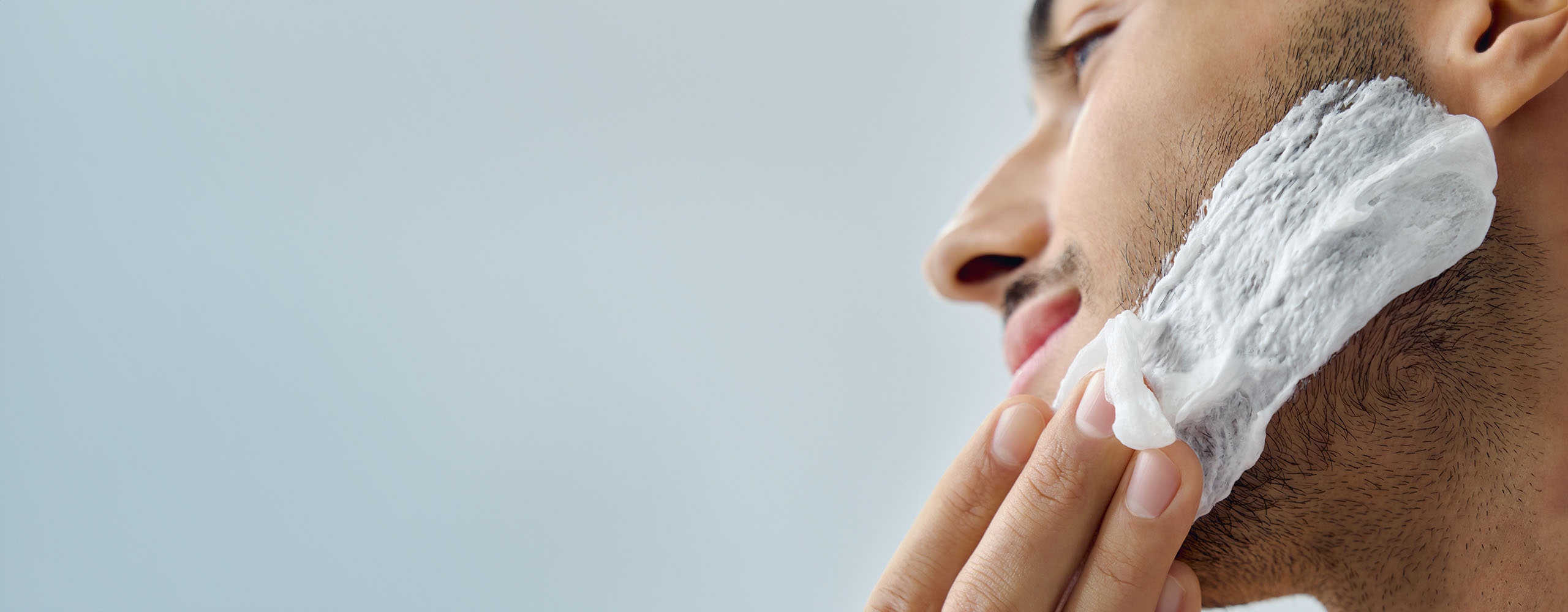 View of a person smearing a NIVEA product onto their face while looking off into the distance.