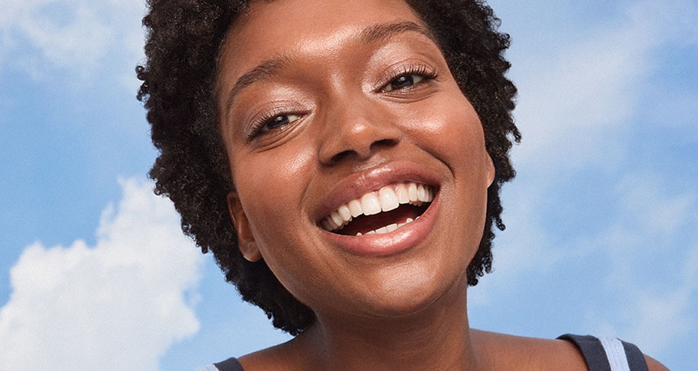 Confident woman with radiant skin posing playfully, promoting the NIVEA LUMINOUS630® range for dewy, glassy skin.