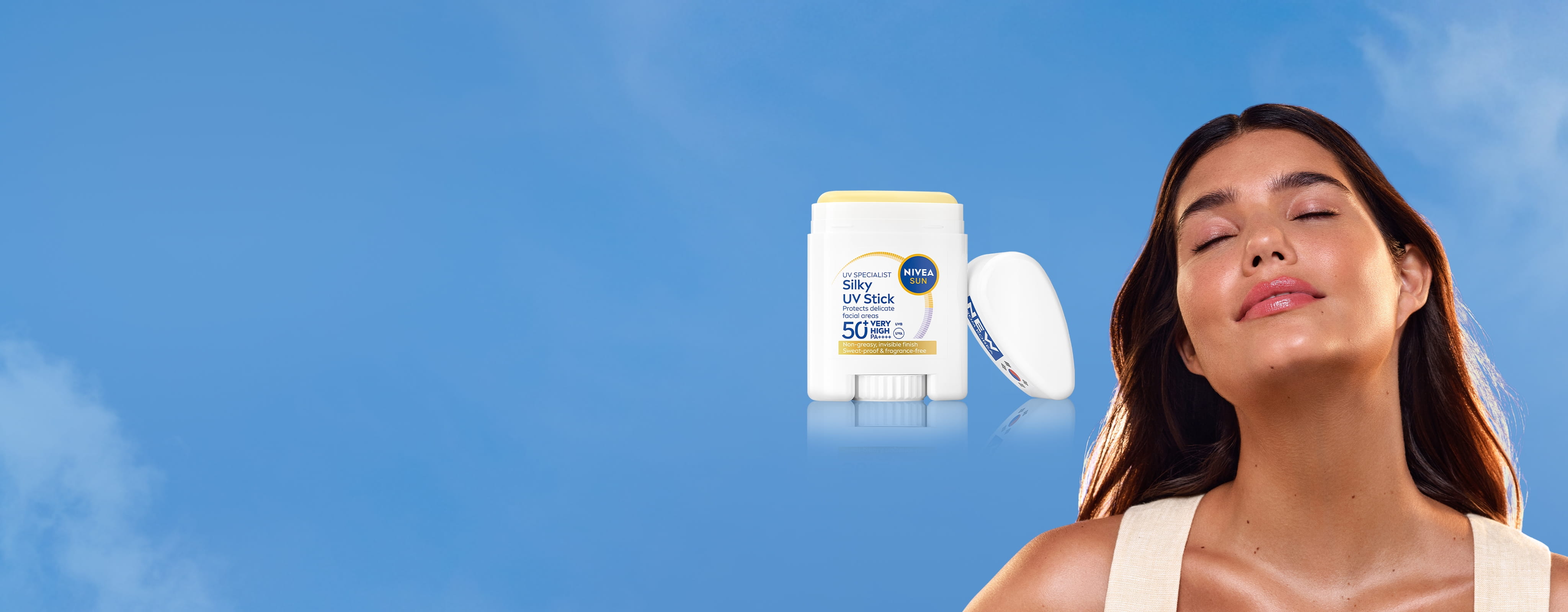 A young woman closes her eyes, tilts her head, subtly smiles, and leans back, basking in the light with glowing skin.