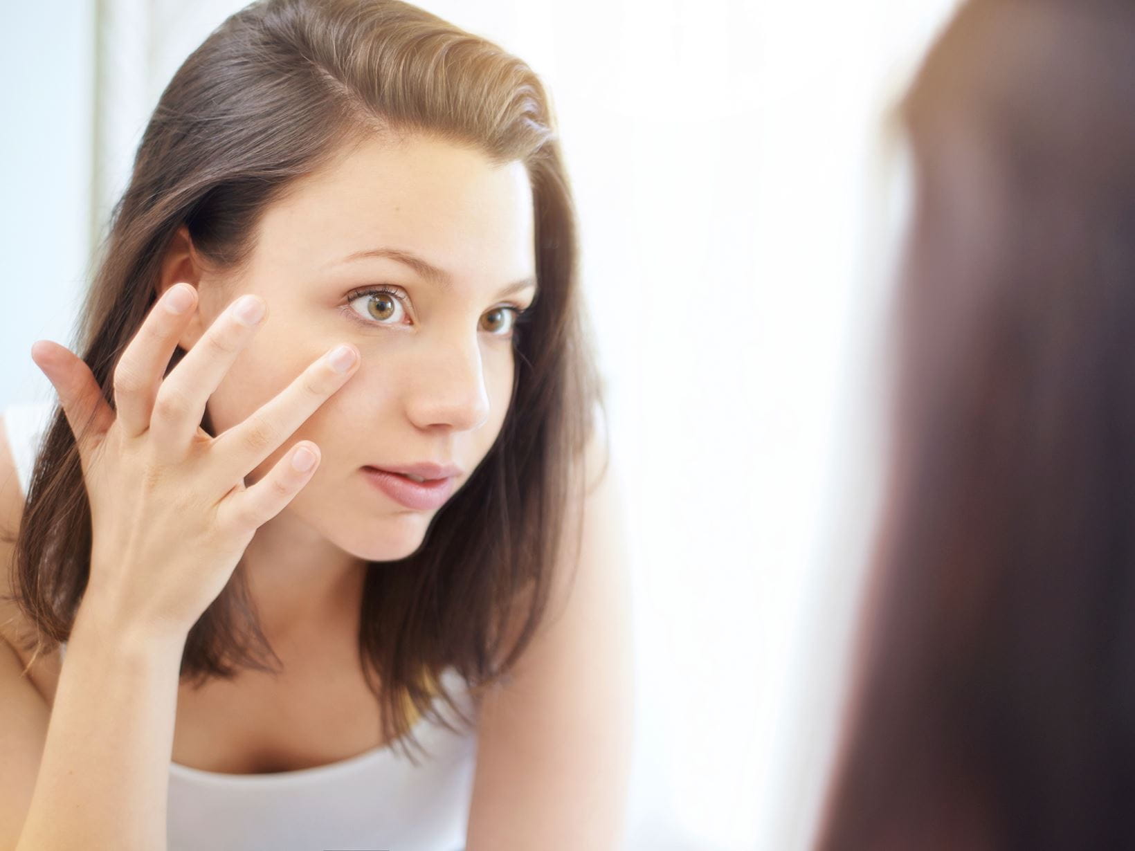 woman putting product on her face