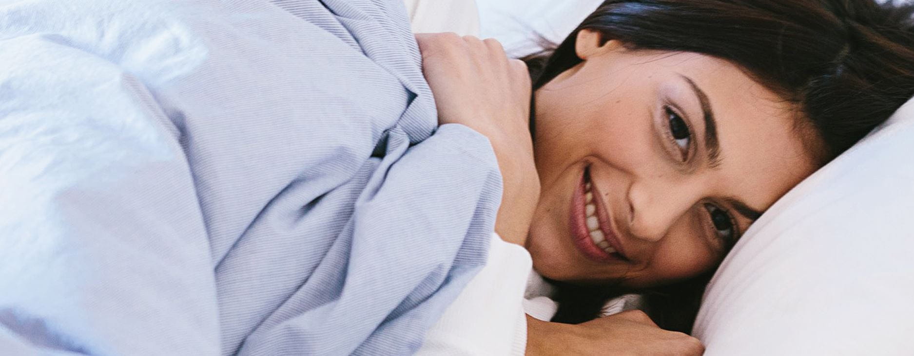 Vrouw in bed met blauwe lakens