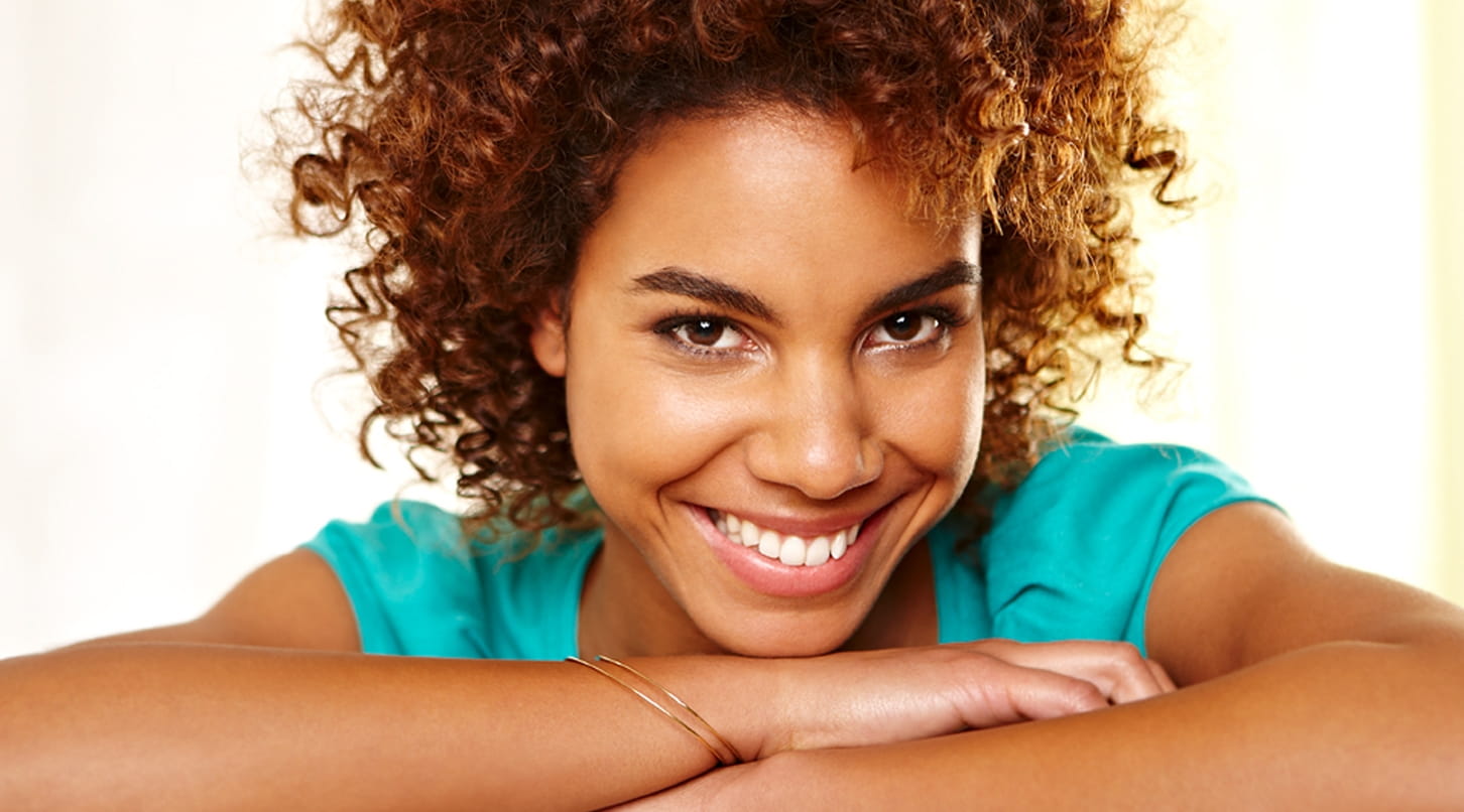 Femme métisse avec cheveux bouclés rigole