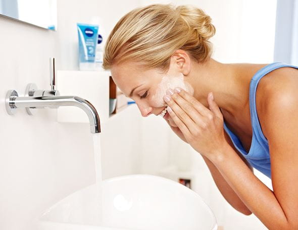 Blonde vrouw wast gezicht in badkamer