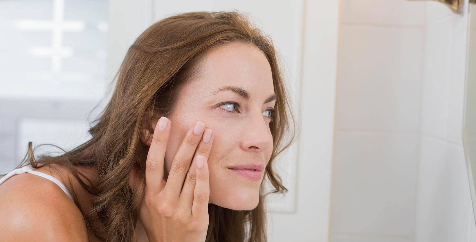 woman looking at her face in the mirror