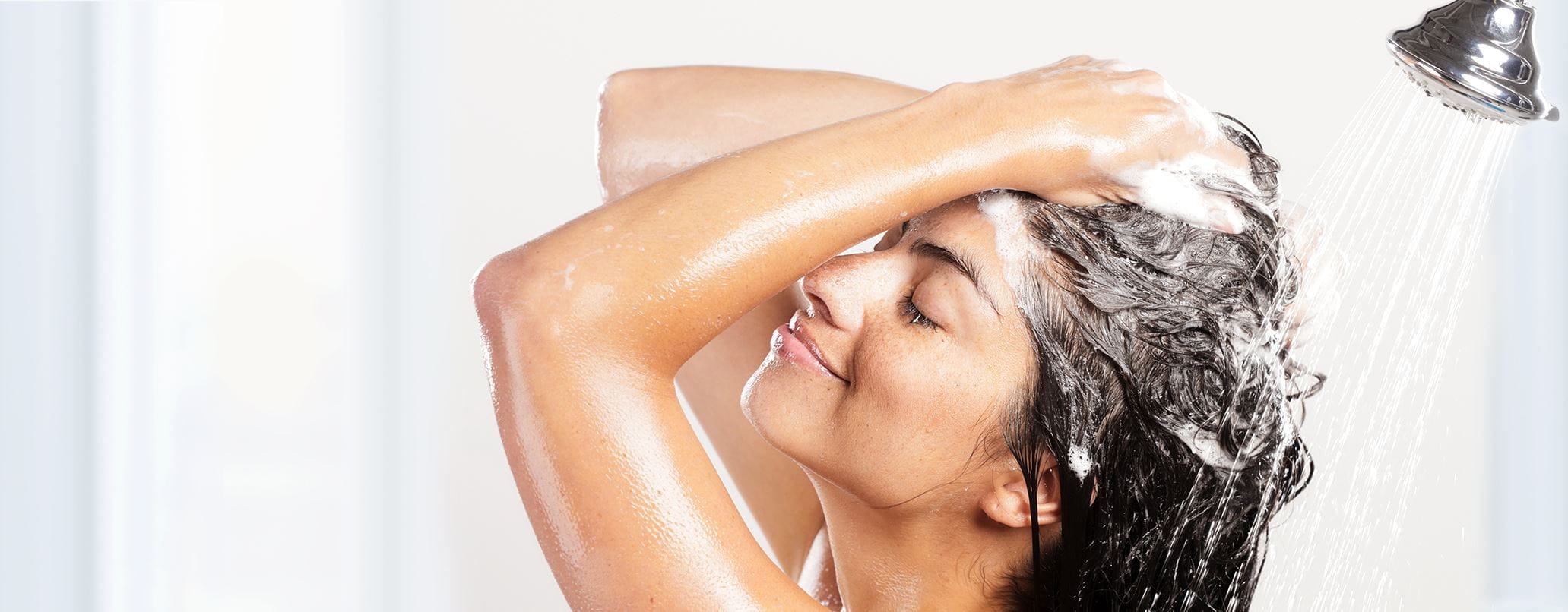 lady washing her hair in the shower with shampoo