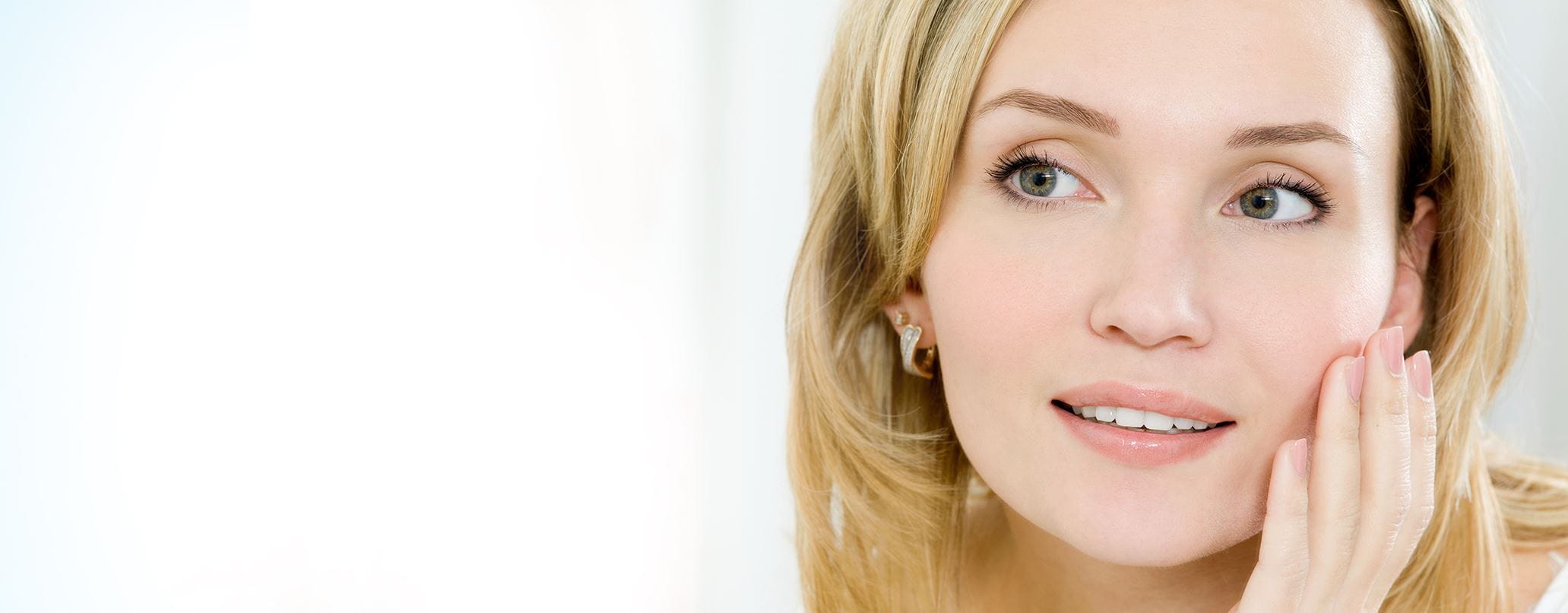 Blonde vrouw met oorringen raakt gezicht aan