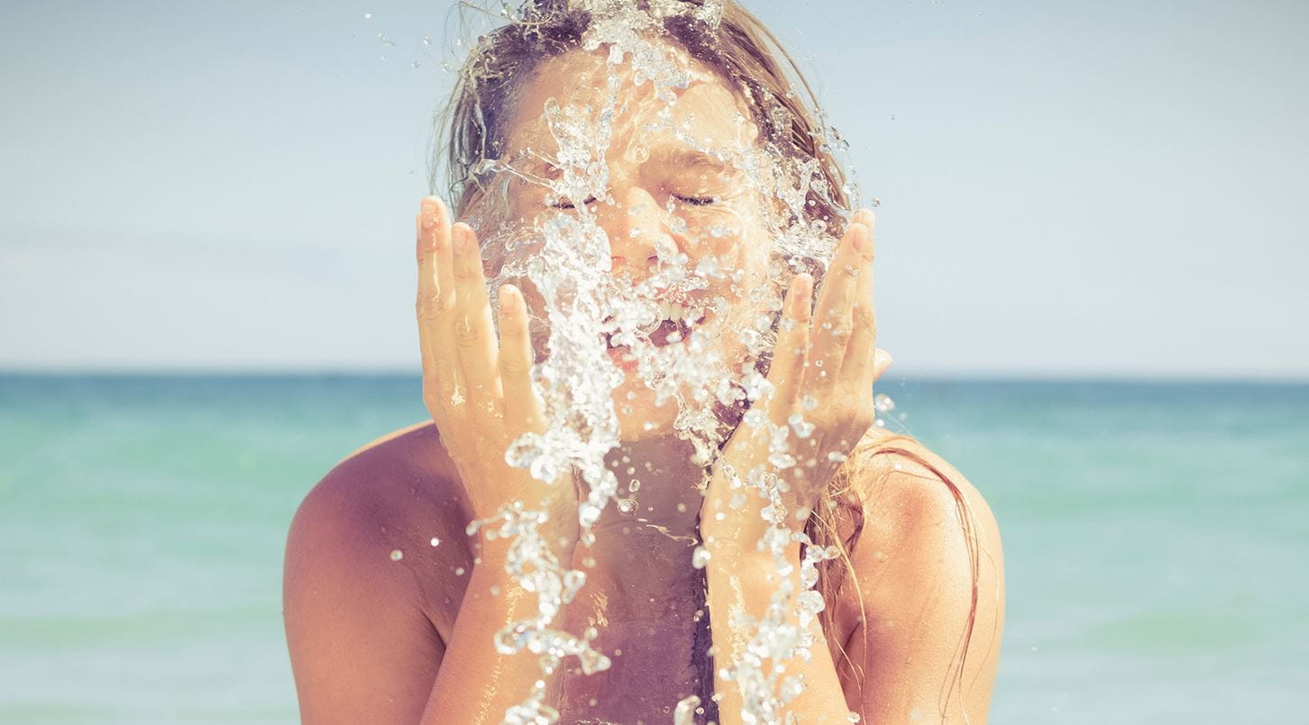 mulher a molhar o rosto na praia