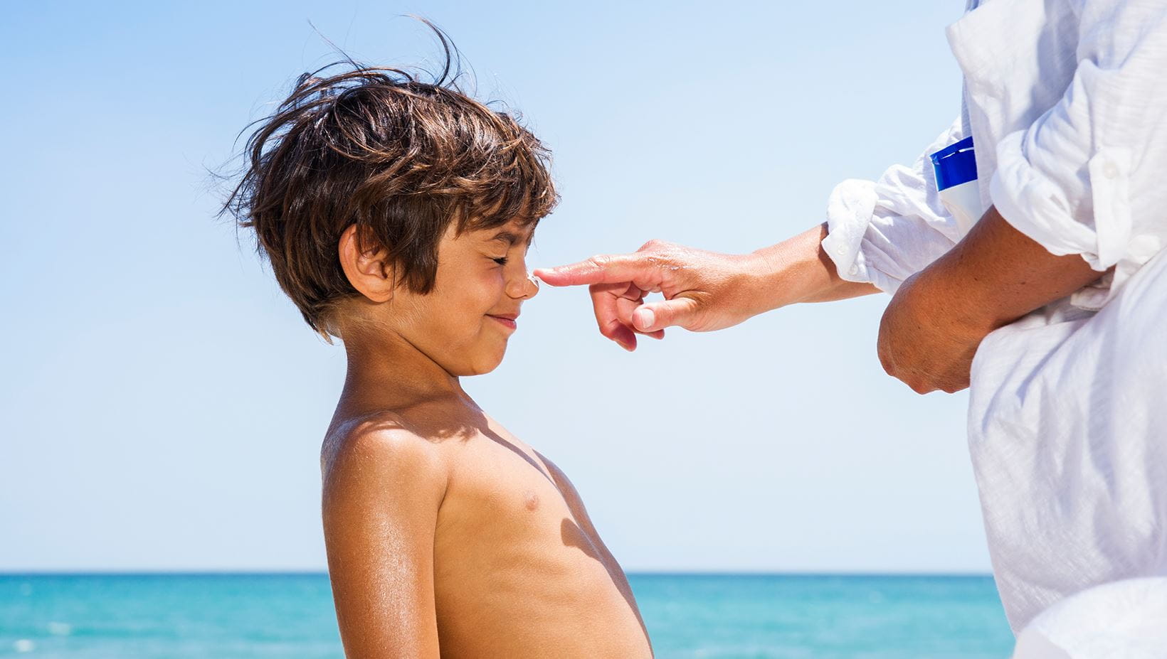 pai a colocar protetor solar no rosto do filho