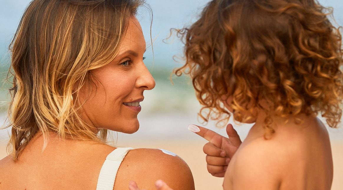 mãe com o filho ao colo na praia