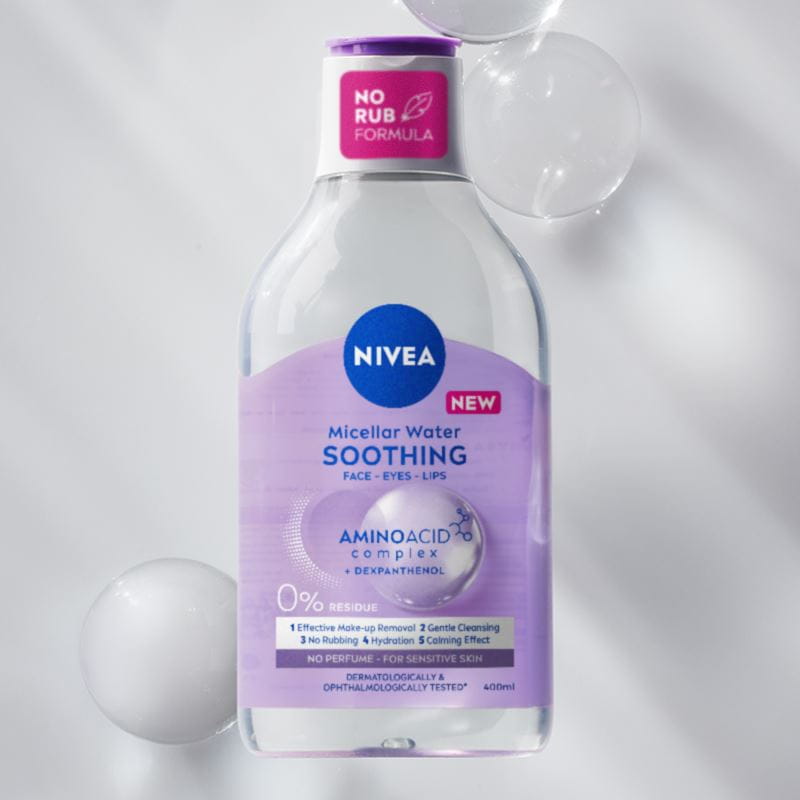 A bottle of NIVEA Micellar Water for Sensitive Skin lays on a purple bubble textured background.